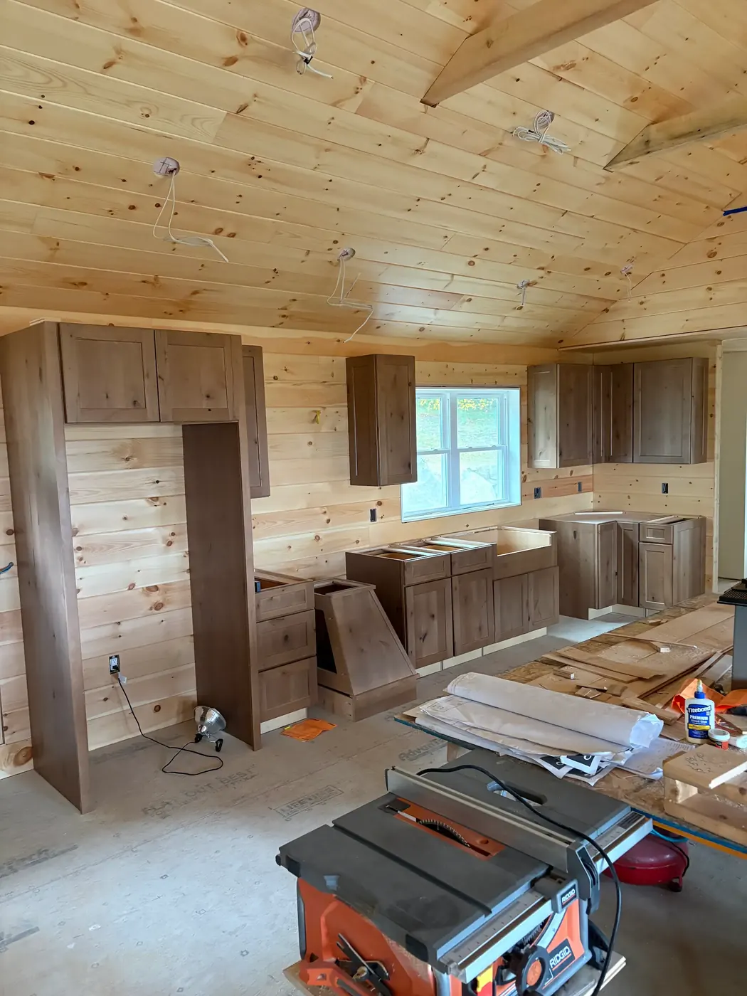 Base, upper and pantry cabinets installed in a pine-paneled room