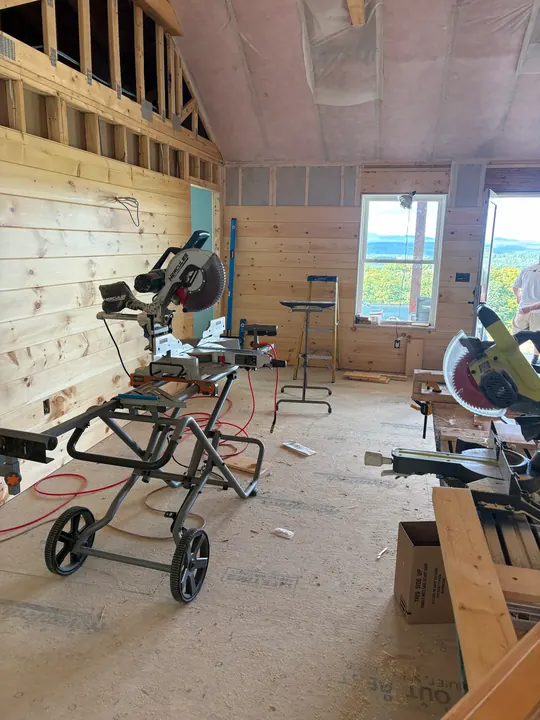 Room with insulation up and the first pine boards on the wall, saws set up