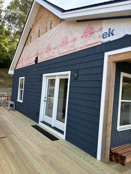 Dark shingle-style siding with white trim around French doors